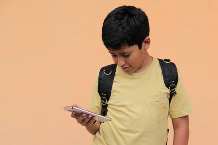 A 10-year-old boy uses his cell phone to play video games, make video calls, send messages, and take...