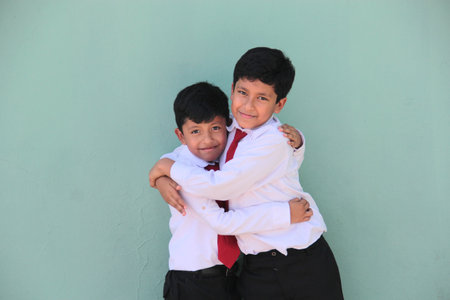 Two dark-skinned Latino boys, elementary school students in uniform, ready for back to school, excited and happyの写真素材