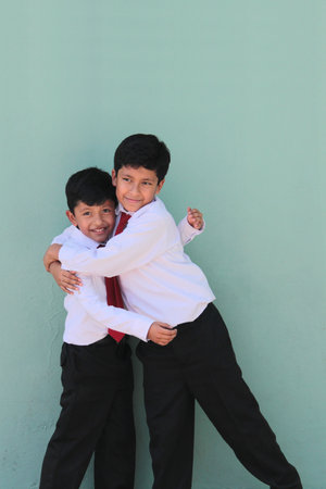 Two dark-skinned Latino boys, elementary school students in uniform, ready for back to school, excited and happyの写真素材