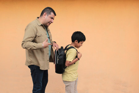 Divorced single dad helps his 10-year-old Latino son with his backpack for back-to-school studiesの写真素材