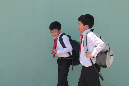 Two dark-skinned boys carry their backpacks and walk back to school to study and learn