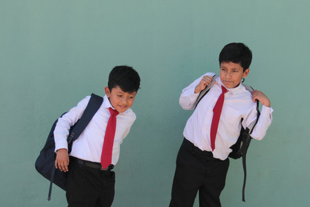 Two Latino boys carry their backpacks and walk back to school to study and learn