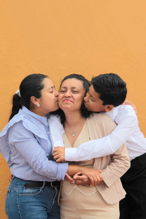 Dark-skinned Latino mother, daughter, and son show their love with hugs and celebrate Mother's Day...