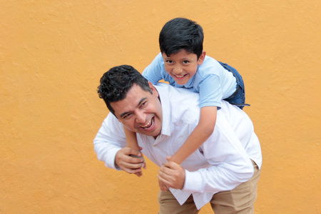 Single dad with his 8-year-old dark-skinned Latino son play and have fun together, celebrating...