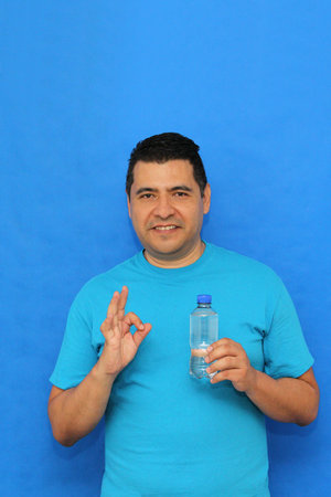 A 40-year-old dark-skinned Latino man shows a plastic bottle of water to stay hydrated and maintain good body functionのeditorial素材