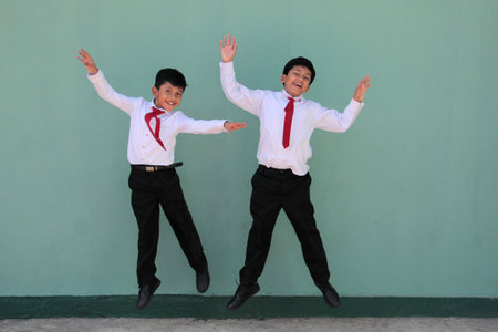 Two dark-skinned Latino male classmates dressed in uniform are excited and happy to be back in schoolの写真素材