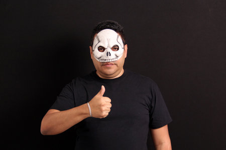 Man wearing a skull mask like Catrin to celebrate the traditional Mexican Day of the Dead shows the...
