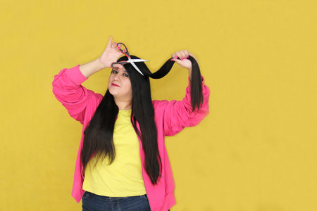 Adult Latina woman with long straight hair uses scissors to cut due to split endsの写真素材