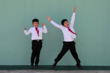 Two dark-skinned male classmates dressed in uniform are excited and happy to be back in school