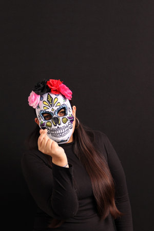 Woman wearing a skull mask makes a heart sign to remember her loved ones on the Day of the Dead in...