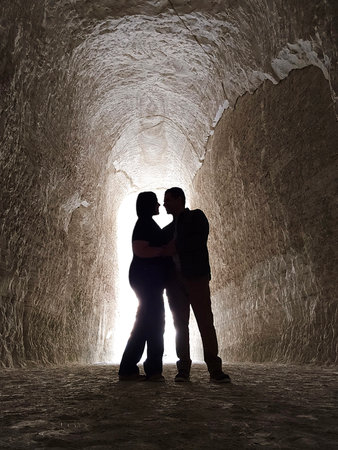 Shadows of a man and woman couple backlit in chalk mines exploring and traveling to celebrate their...