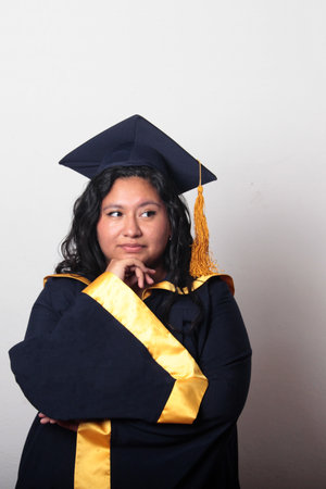 Young woman dressed in cap and gown appears pensive and thoughtful