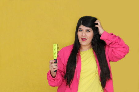 30-year-old Latina woman brushes her long, straight hair, suffering from damaged, dehydrated, and...