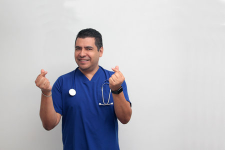 Dark-skinned Latino male doctor, a cardiologist, makes heart-shaped hand gesturesの写真素材