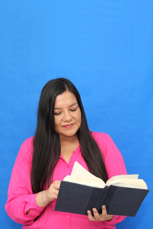 40-year-old Latina woman with a book in her hands to read, learn, and gain knowledgeの写真素材