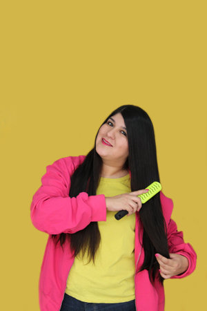 Latina woman brushes her long, straight hair, suffering from damaged, dehydrated, and tangled hairの写真素材