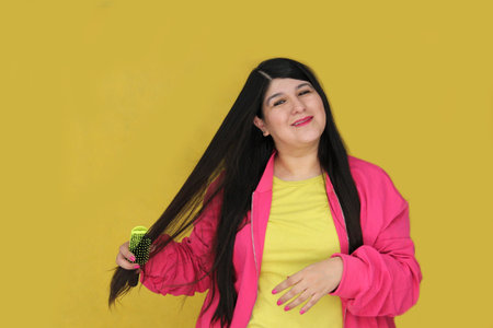 30-year-old Latina woman brushes her long, straight hair, suffering from damaged, dehydrated, and...