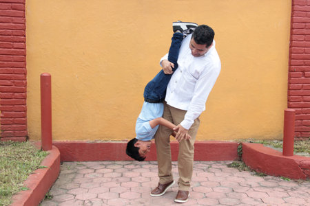 Single dad with his 8-year-old dark-skinned Latino son play and have fun togetherの写真素材