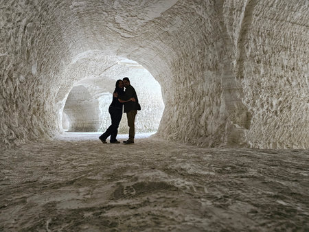 Shadows of a man and woman couple backlit in chalk mines exploring and traveling to celebrate their...