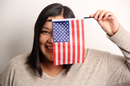 40-year-old Latina woman proudly displays the United States flag as a symbol of migration and freedomの写真素材