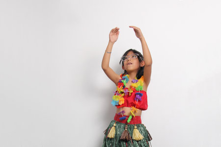5-year-old Latina girl with brown hair enjoys learning to dance Hawaiian, wearing a colorful skirt and leis, and shows off her movesの写真素材