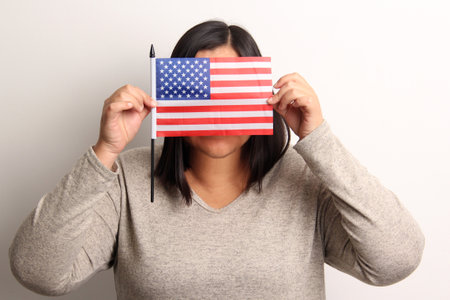 40-year-old Latina woman proudly displays the United States flag as a symbol of migration and...