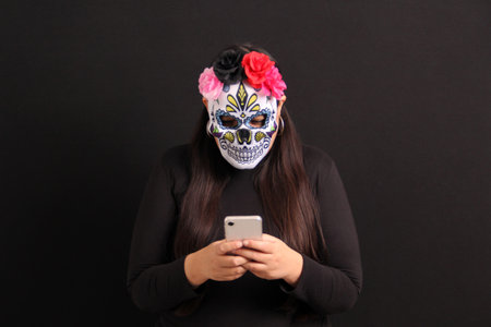 Mexican adult woman with Catrina mask shows her cell phone to see Day of the Dead promotions and discounts in Mexicoの写真素材