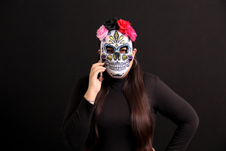 Mexican adult woman with Catrina mask shows her cell phone to see Day of the Dead promotions and discounts in Mexicoの写真素材