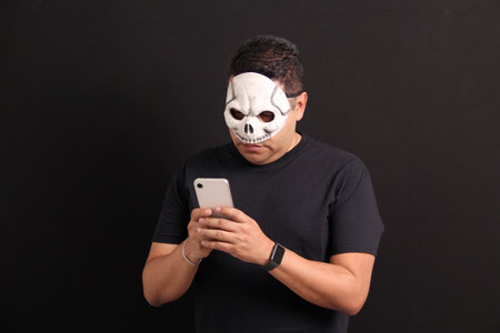Mexican man with skull mask uses his cell phone to take advantage of Day of the Dead promotions and discounts in Mexicoの写真素材