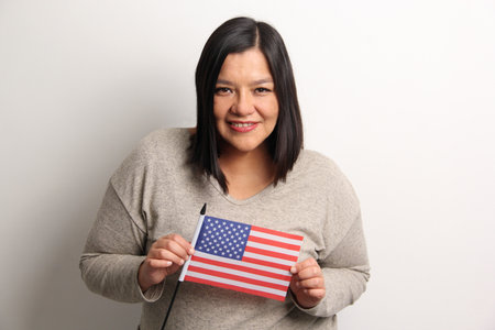 40-year-old Latina woman proudly displays the United States flag as a symbol of migration and freedomの写真素材
