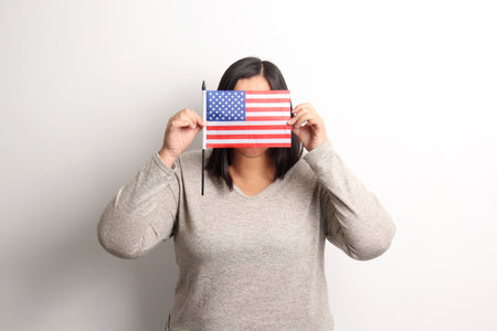40-year-old Latina woman proudly displays the United States flag as a symbol of migration and freedomの写真素材