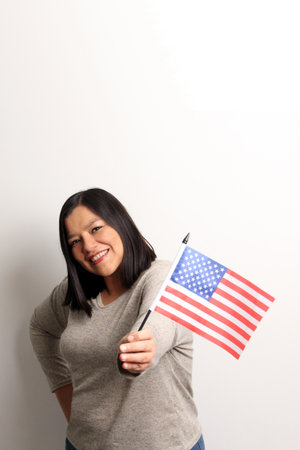 40-year-old Latina woman proudly displays the United States flag as a symbol of migration and freedomの写真素材