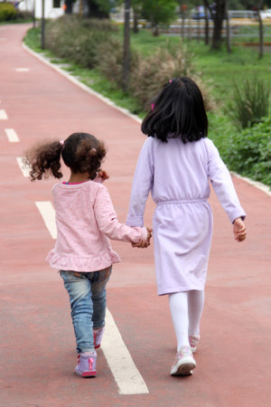 Brunette Latina 4 and 5 year old girls walk holding hands like sisters and friends spending time together outdoorsの写真素材