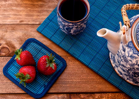 Set of teapot and chinese tea cups with strawberry tea.