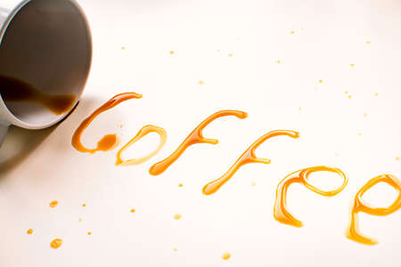 Coffee cup lying with the word coffee written with coffee on white background.の写真素材