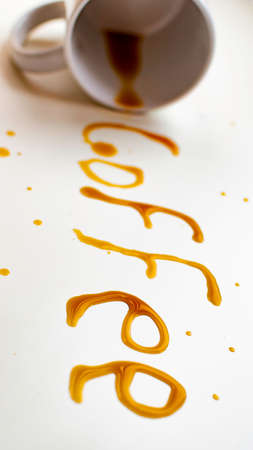 Coffee cup lying with the word coffee written with coffee on white background.の写真素材