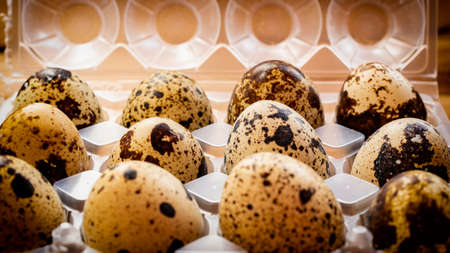 Three quail eggs with wooden bottom inside their egg cup.