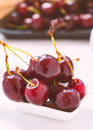 Red cherries on a white spoon, on a wooden table