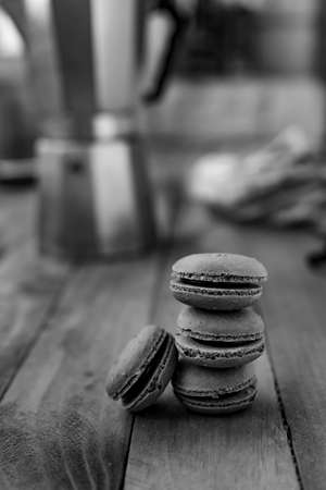 Macarons on a wooden table with a coffee pot, with a black and white style.の写真素材