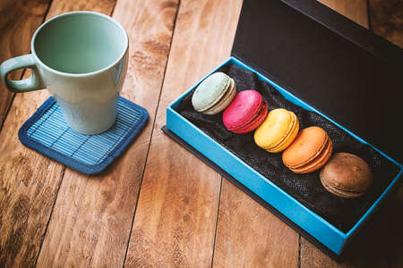 Macarons of different colors presented inside a box, with a vintage background on a table of madrasの写真素材