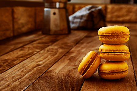 Orange macarons on a wooden table with a coffee pot, with a vintage style.の写真素材