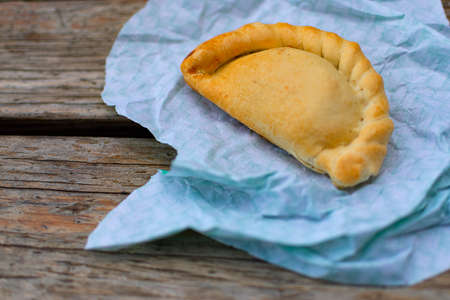 Meat pie with a dish wrap, on top of an old wooden table.