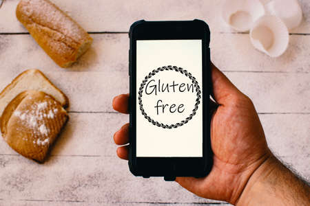 Gluten free concept. Hand holding a mobile phone with the gluten-free icon.の写真素材