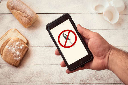 Gluten free concept. Hand holding a mobile phone with the gluten-free icon.の写真素材