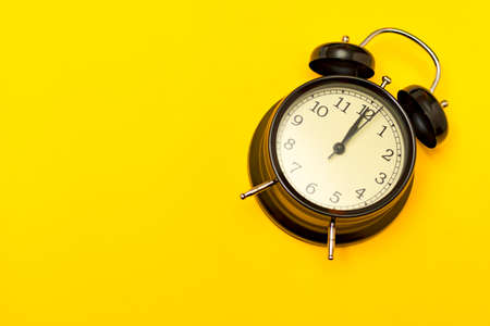 Black alarm clock on yellow background. Concept time.の写真素材
