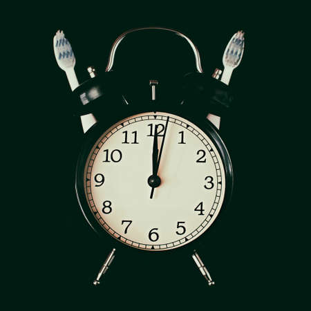 Dental hygiene time concept. Black alarm clock with black background.の写真素材