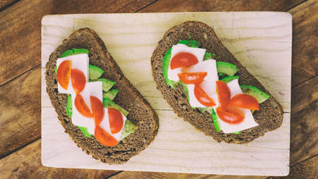 Slice of bread with avocado fresh cheese and cherry tomatoes