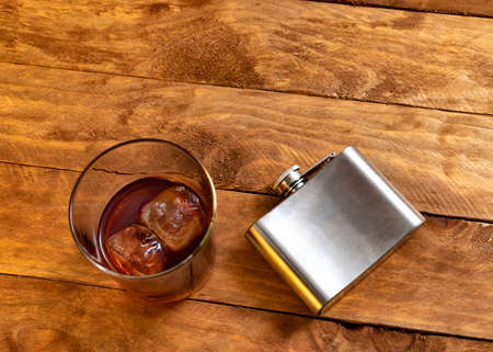 Alcoholism concept. Glass tumbler with whiskey and ice next to a liqueur flask.の写真素材