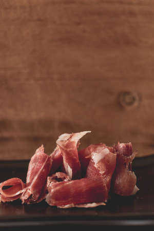 Serrano ham chips on a plate over old wood.の写真素材