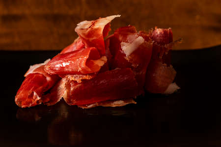 Serrano ham chips on a plate over old wood.の写真素材